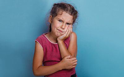Young child holding cheek in pain